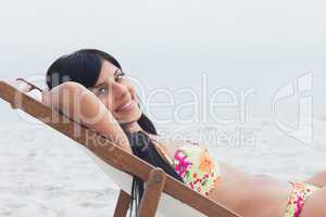 Smiling woman resting on deck chair