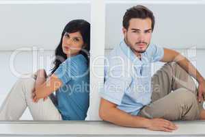 Unhappy couple are separated by white wall