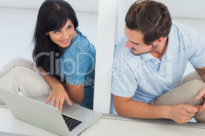 Smiling woman showing something on laptop at her boyfriend