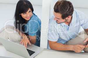 Smiling woman showing something on laptop at her boyfriend