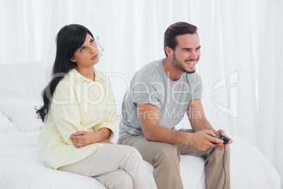 Annoyed woman looking up during her boyfriend playing video game
