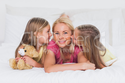 Twins kissing their mother in bed