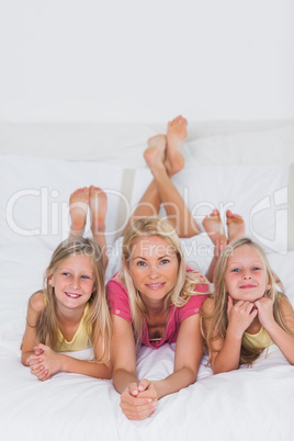 Twins lying with their mother in bed
