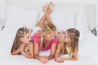 Twins relaxing with their mother in bed
