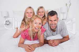 Portrait of parents lying in bed with their twins