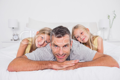 Cheerful man with his twins in bed