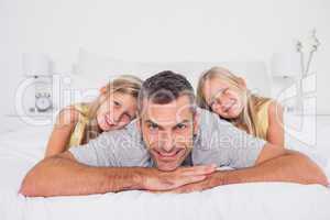 Cheerful man with his twins in bed
