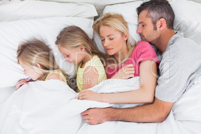 Parents sleeping in bed with their twins