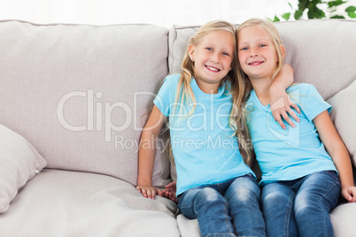Blonde twins sitting on a couch