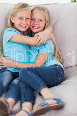 Young twins embracing each other on a couch