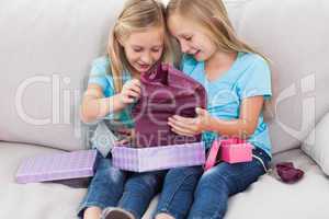 Young twins unwrapping birthday gift sitting on a couch