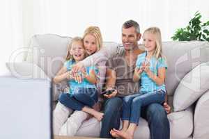 Cute twins and parents watching television