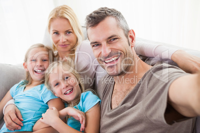 Man taking picture of wife and twins sitting on a couch