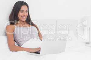 Woman using her laptop in bed