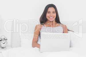 Portrait of an attractive woman using her laptop in bed