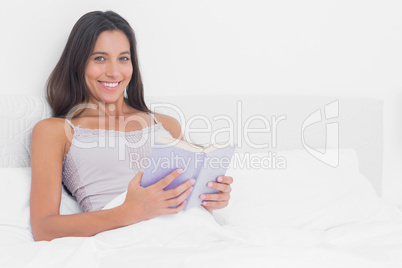 Portrait of a woman reading a book in bed