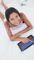 Woman using her tablet in bed
