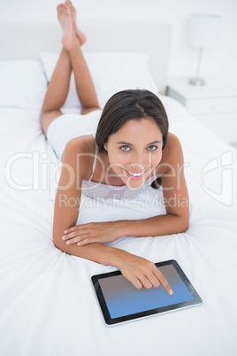 Woman using her tablet lying in bed