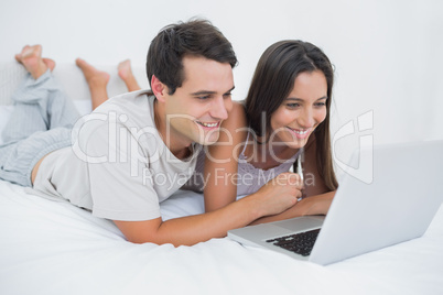 Couple using the laptop lying bed