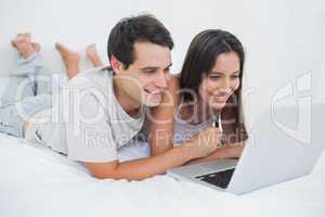 Couple using the laptop lying bed