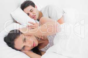 Woman covering ears while her partner is snoring