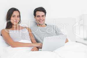 Portrait of a cheerful couple using a laptop