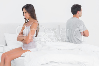 Couple sitting on their opposite sides on bed
