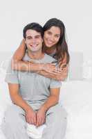 Woman embracing her partner sat in bed