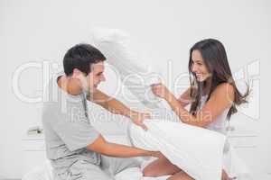 Couple fighting together with pillows
