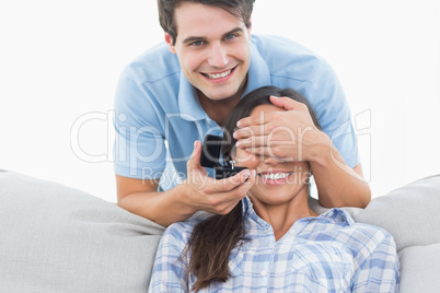 Man hiding his girlfriends eyes and offering her an engagement r