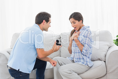 Man on bended knee offering an engagement ring to his partner