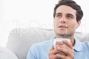 Man holding a cup of coffee sat on the couch