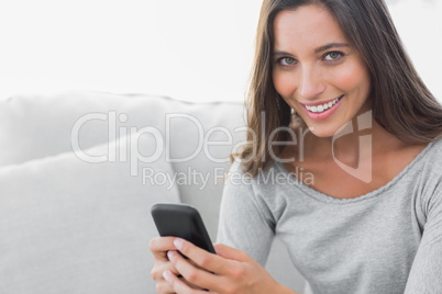 Woman texting while she is sat on a couch