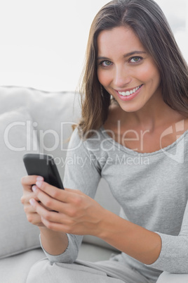 Woman texting while she is sat on a sofa