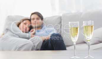 Couple relaxing on a couch with flutes of champagne