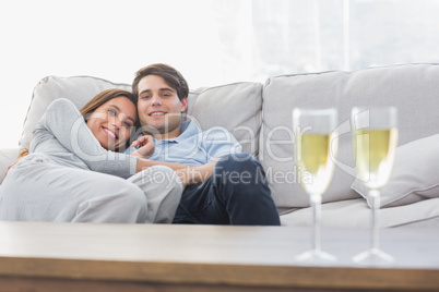 Beautiful couple resting on a couch with flutes of champagne