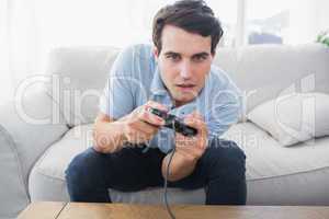 Man having fun with video games while he is sat on a sofa