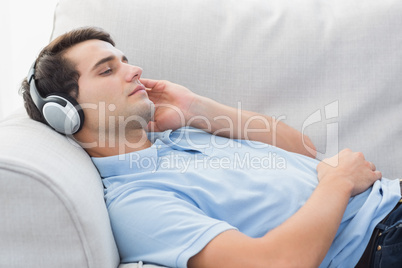 Man enjoying music lying on a couch