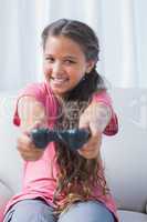 Smiling little girl playing video game on sofa