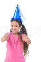 Smiling little girl wearing blue hat for a party and does thumbs