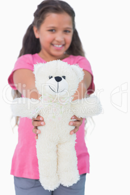 Cute little girl showing her teddy bear to camera