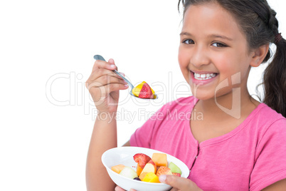 Smiling little girl eating fruit salad