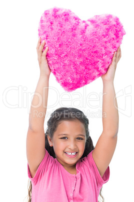 Smiling little girl holding cushion in the shape of a heart