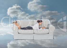 Businesswoman lying on couch and typing on her laptop