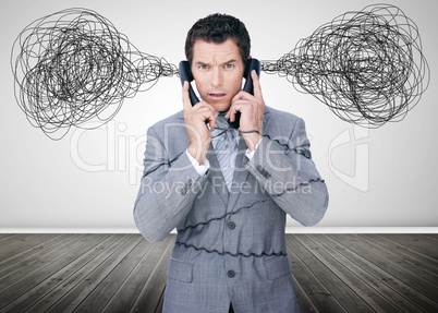 Overworked businessman holding two telephones