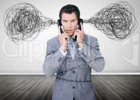 Overworked businessman holding two telephones