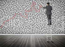 Businessman standing on a ladder solving maze puzzle