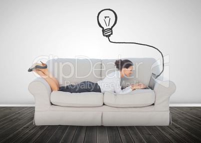 Attractive businesswoman lying on a couch and typing on her lapt