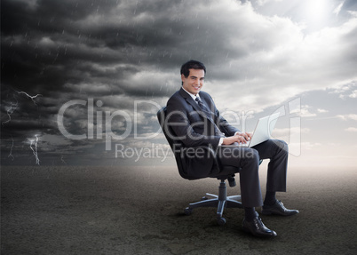 Attractive businessman using his laptop outside during stormy we