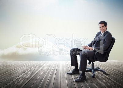 Handsome businessman sitting on a swivel chair and using his lap